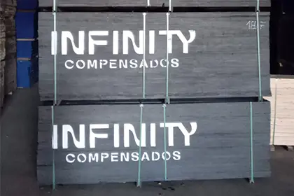 Pallets de compensado plastificado com filme fenólico preto, embalados e cintados, com marca “Infinity Compensados” nas chapas (estoque/expedição).